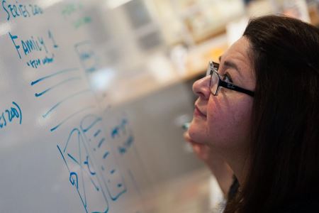 A square image of Cynthia starring up at a whiteboard.