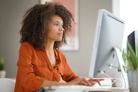Woman typing on a desktop computer