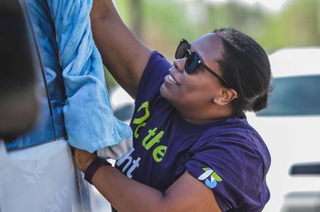 Tia washing a car while volunteering