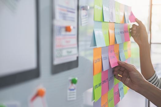 An image of hands pulling sticking notes off a whiteboard.