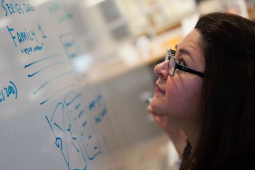 A square image of Cynthia starring up at a whiteboard.