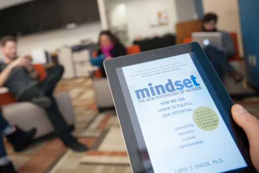 Closeup of a hand holding a electronic notebook with the book "Mindset: The New Psychology of Success"" on screen