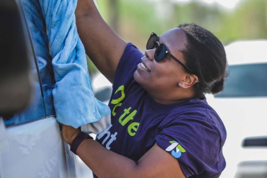 Tia washing a car while volunteering