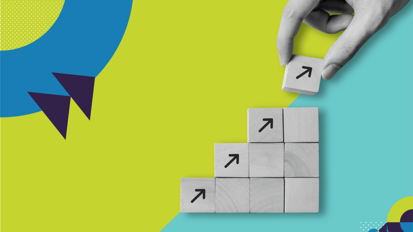 Photograph of a hand placing building blocks upward on a blue and green background.