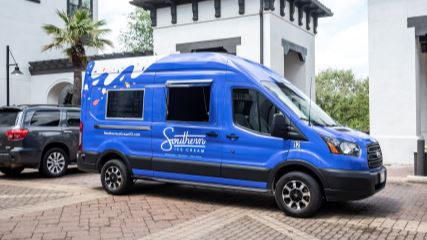 Photograph of a deep blue van labeled with the Southern Ice Cream logo in white cursive font