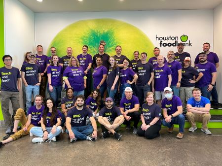entire BE team, wearing purple t-shirst, in front of a green backdrop at the Houston Food Bank