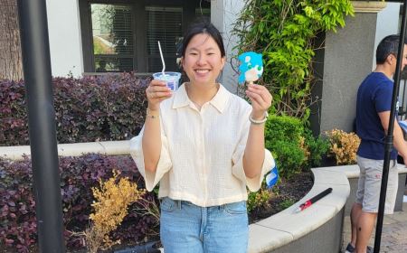 Holly wearing a cream colored shirt holding up a cup of ice cream and a popsicle at the Southern Ice Cream photo shoot