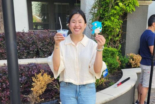 Holly wearing a cream colored shirt holding up a cup of ice cream and a popsicle at the Southern Ice Cream photo shoot