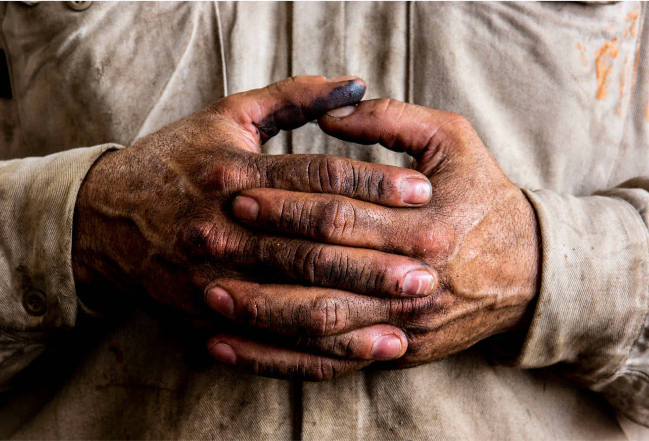 A close up of an Archrock employees hands from working hard at a rig