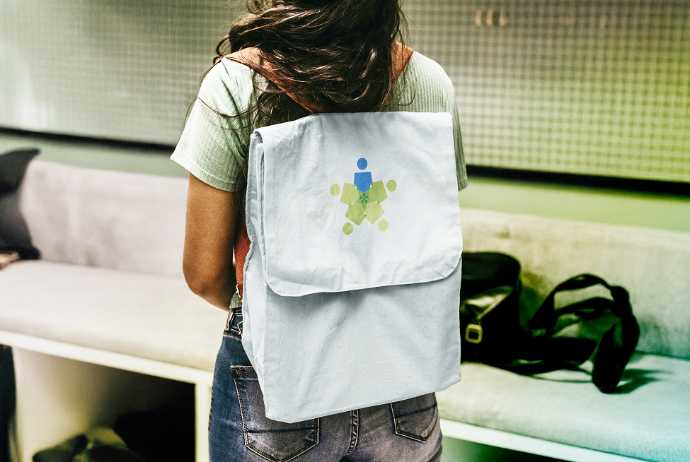 Student wearing gray backpack with Data Projections human connectivity logo in blue and lime green at school campus