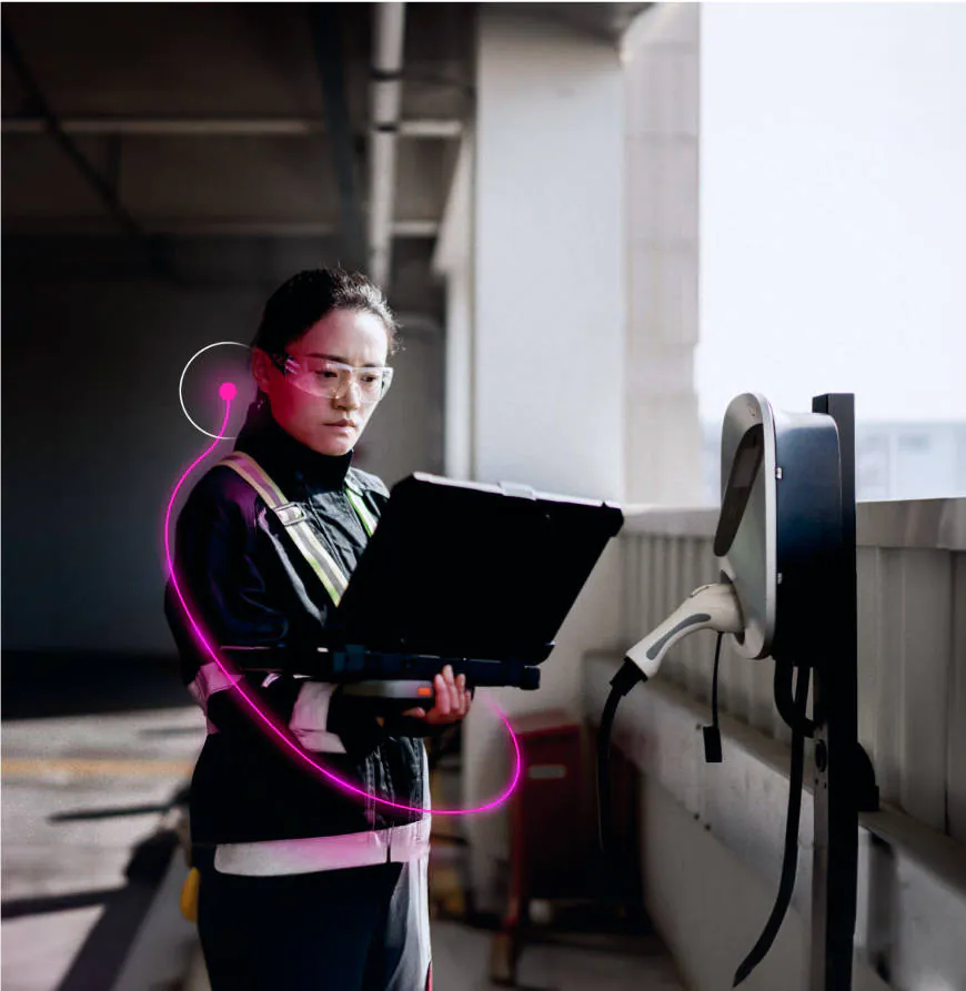 A Lynkwell technician working on a large tablet while looking at a charging station