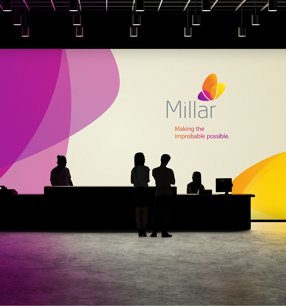 Large illuminated Millar trade show wall with butterfly logo and ‘Making the improbable possible’ tagline behind silhouetted people at a reception desk.