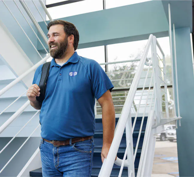An S&B employee walkig down a flight of stairs with a company shirt on designed by BrandExtract
