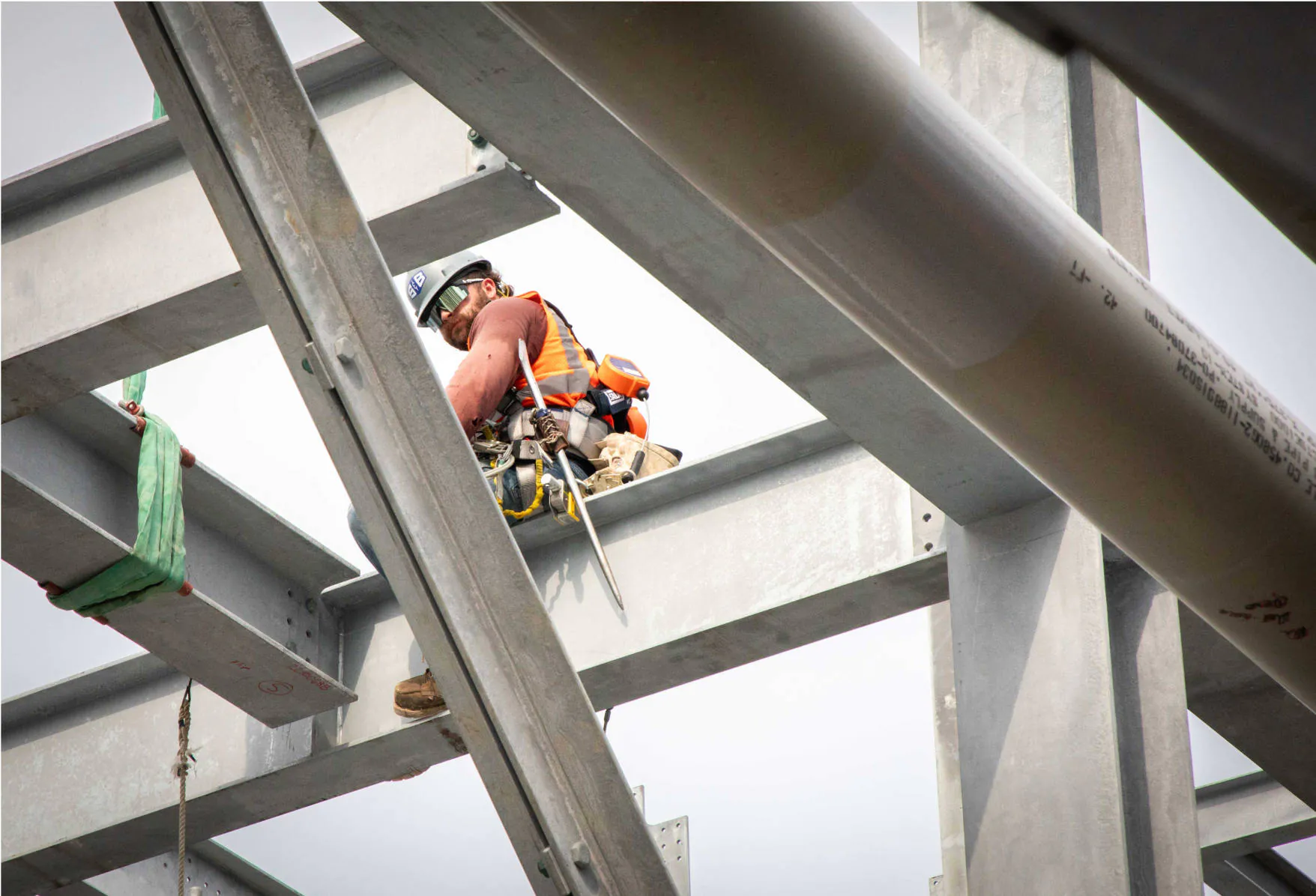 An S&B construction worker sitting on a steel girder