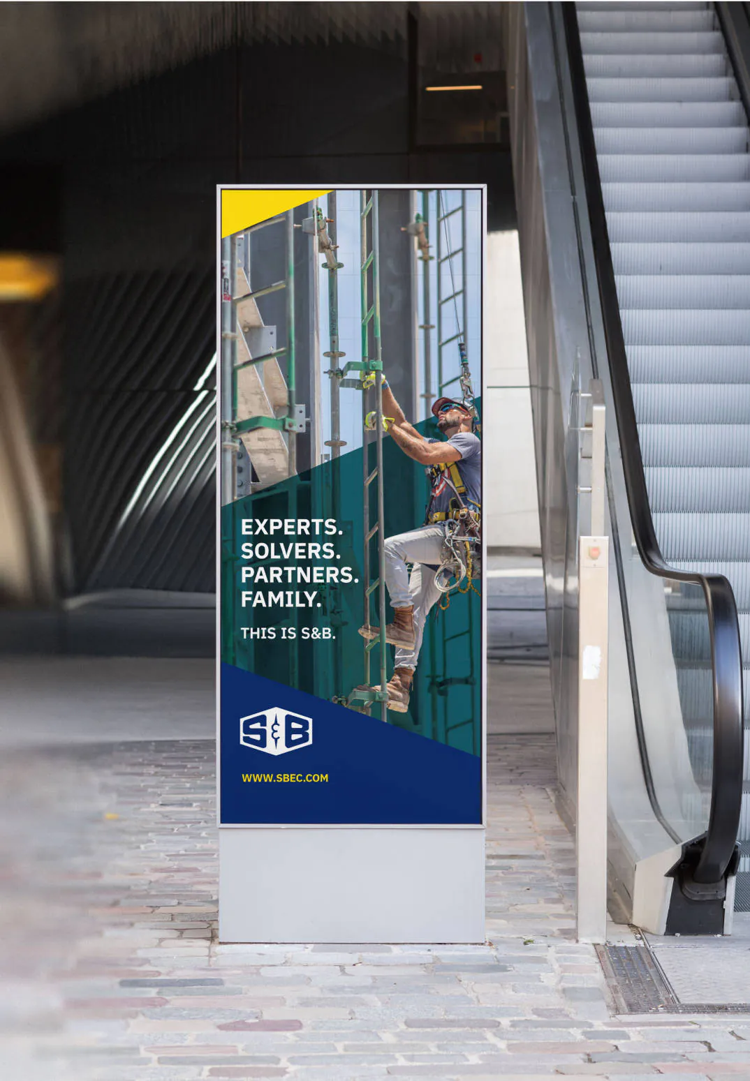 A digital stand next to an escalator with the an S&B 