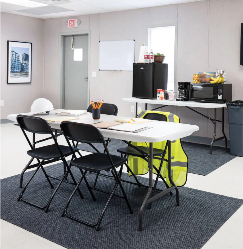 A small table with fold out chairs surrounding in a makeshift break room in a WillScot modular space