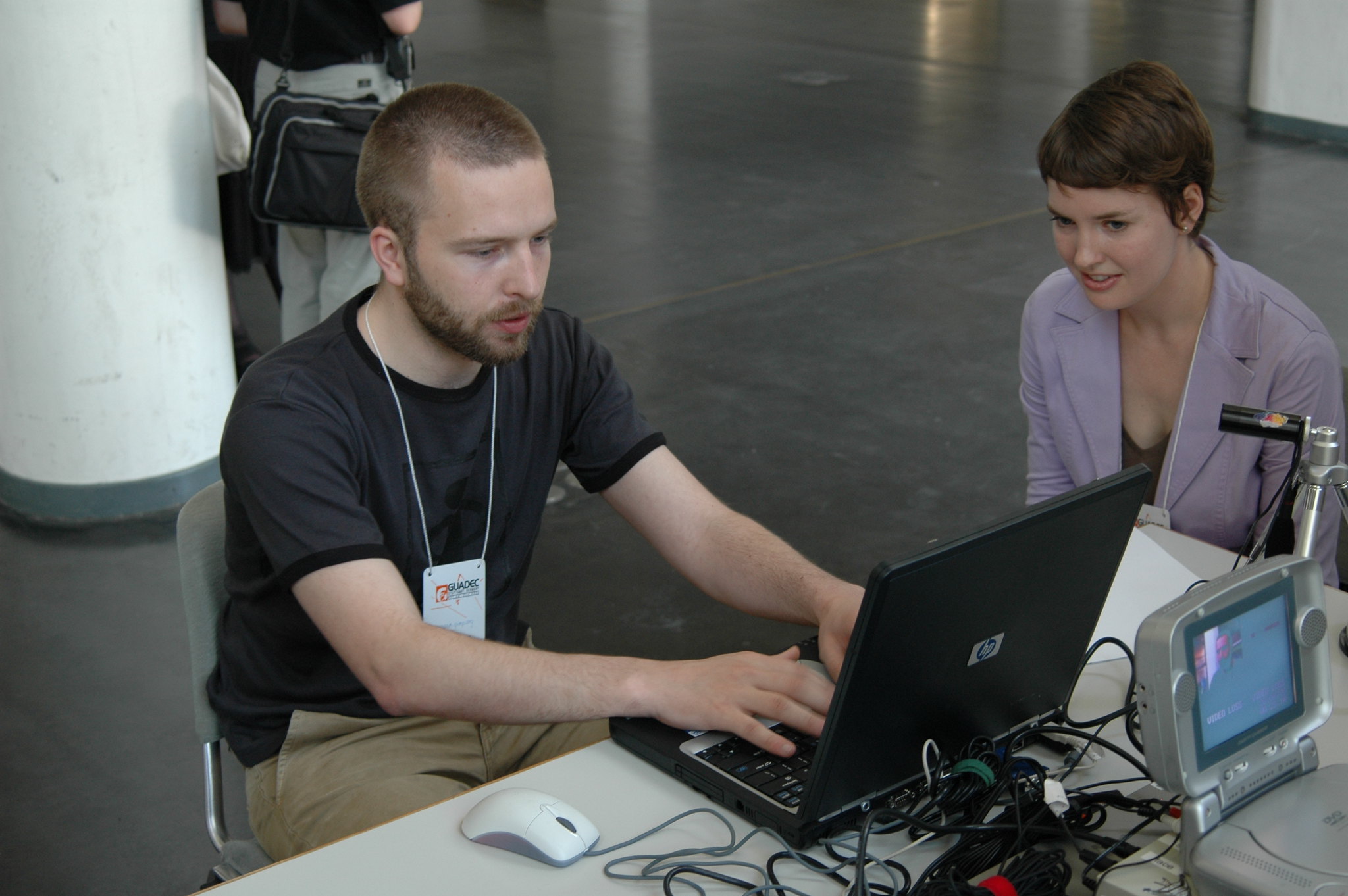 Photo of a caucasian man sitting at a table performing a usability test by using a laptop in front of a female observer