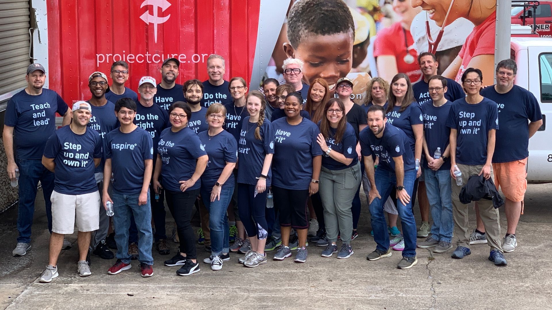 The BrandExtract team standing against a Project C.U.R.E. trailer.