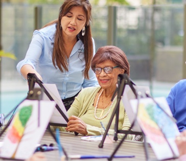 A Belmont Village employee and resident painting together 