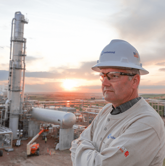 A Crestwood employee standing next to a refinery 