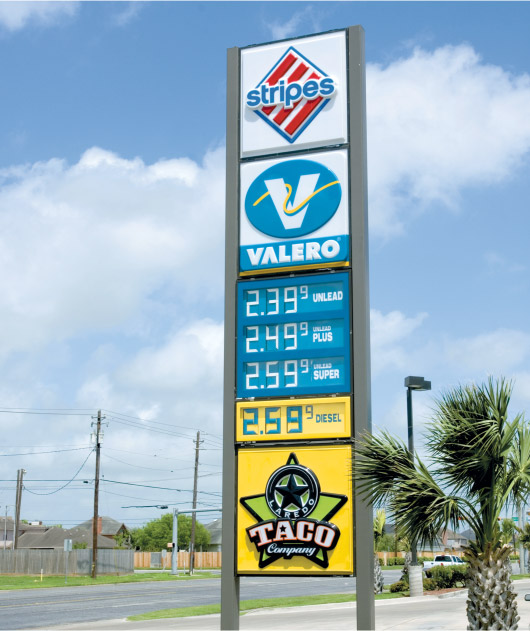 A Stripe's sign with the logo sitting at the top of a gas station price board.